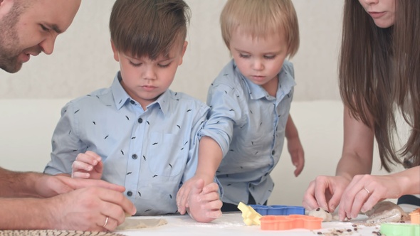 Young happy parents showing their children how to make cookies