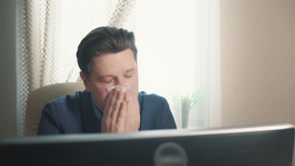 Man Blowing His Nose Into a Tissue