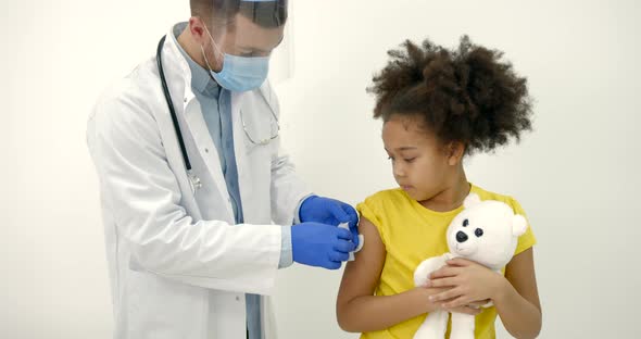 Male Pediatrician Giving a Vaccine Shot to a Black Kid