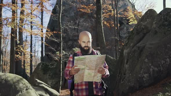 Handsoome Man Wearing a Beard Keeps a Tourist Map in His Hands
