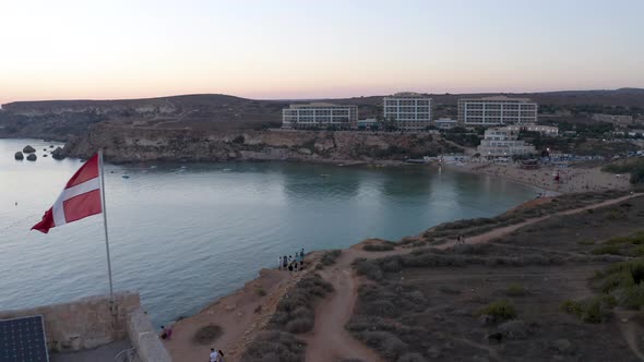 Tower with flag of the Order of Malta knights above Golden Bay,aerial.