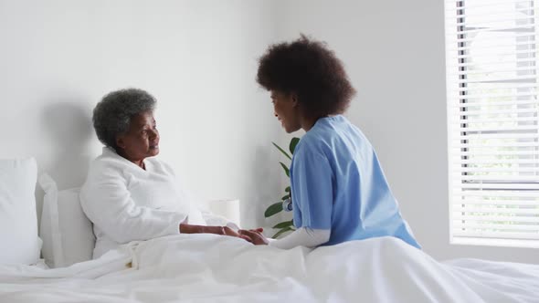 Caring african american female doctor talking to senior african american female