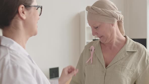 Doctor Giving Pink Ribbon to Woman with Cancer