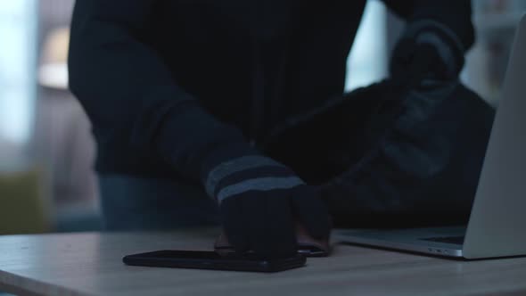 Close Up Of A Thief Man Holding Flashlight Stealing Wallet, Smartphone, And Laptop