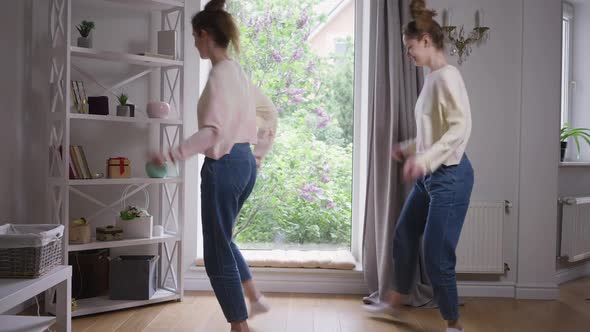 Wide Shot Portrait Two Charming Beautiful Identical Twins Dancing in Living Room Looking at Camera