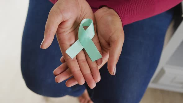 Video of hands of plus size african american woman holding blue ribbon