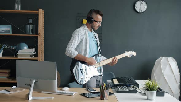Slow Motion Portrait of Attractive Man Performer Playing Guitar and Keyboard Recording Music