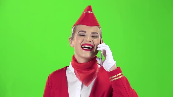 Stewardess in a Red Suit Speaks on the Phone . Green Screen. Slow Motion