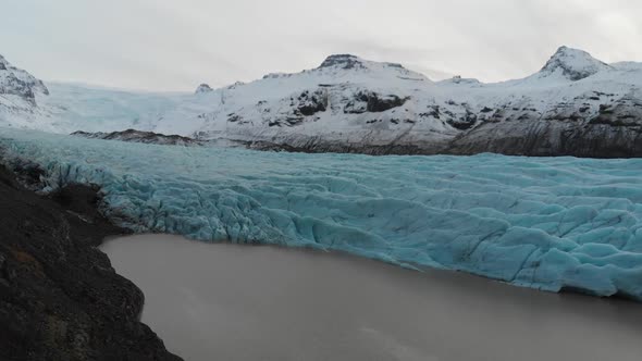 Aerial View, Svinafellsjokull Glacier, Iceland. Blue Ice, Snow Capped Hills and Glacial Melted Water