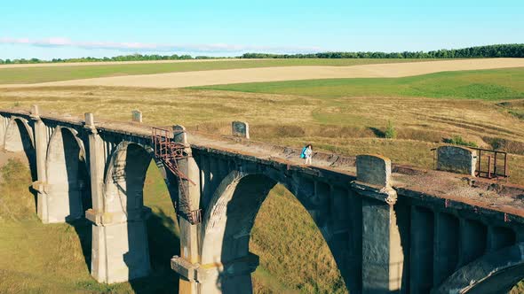 A Lady is Walking Along a Deserted Bridge with Sports Inventory