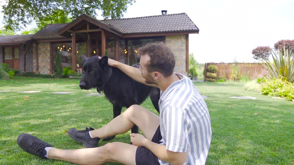 Young man loving his dog on the grass.