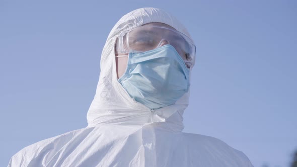 Close-up Portrait of Young Caucasian Man in White Safety Suit and Protective Eyeglasses at the