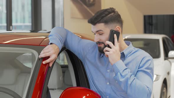Bearded Man Talking on His Phone at Car Dealership