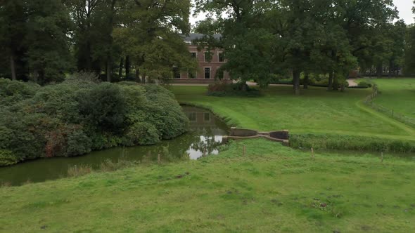 Low aerial over beautiful castle garden with a large mansion in the background