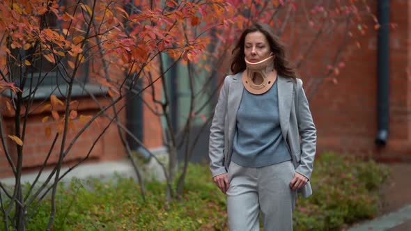 Woman with Neck Brace Is Walking on Street at Autumn Day, Curing Otheohodrosis By Sedentary