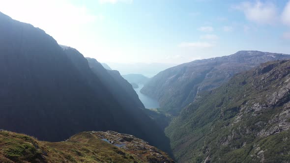 Moving backward over head of beautiful woman standing on cliff in magnificent dramatic Norway mounta