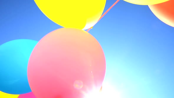 Slow Motion Solid Colored Inflatable Balloons From Below, With Out Of Focus Background Of A Sunny