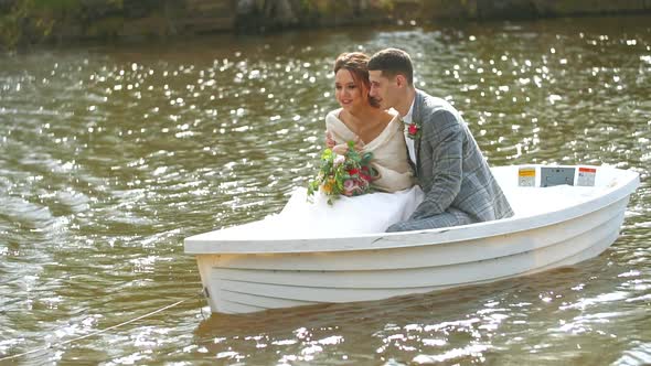 Girl with a Bouquet and Her Husband Are Swimming in a Pond. Newlyweds Are Happy