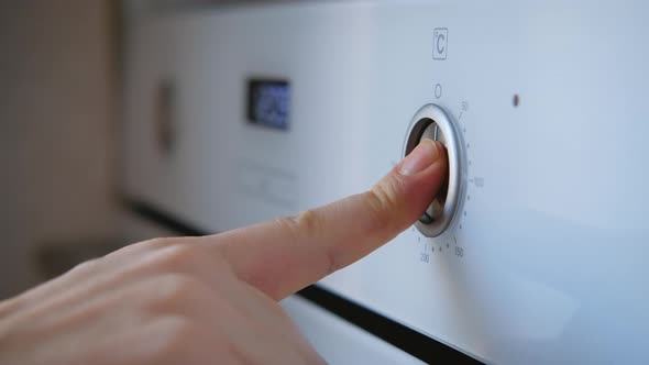 Closeup of female hand turns the oven switch sets temperature