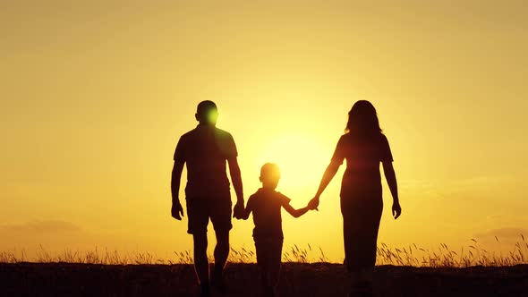 The Father and Mother Hold Their Son's Hands and Go To Meet the Setting Sun, Silhouette of a Happy