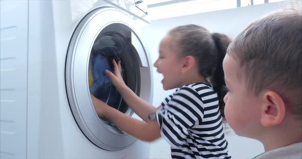 Cute Children Looks Inside the Washing Machine. Cylinder Spinning Machine. Concept Laundry Washing