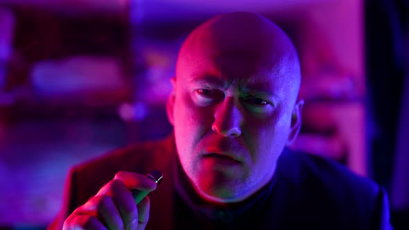 Serious Man in Nightclub Smoking Ecigarette Vaping Closeup Portrait with Neon Lights on Face