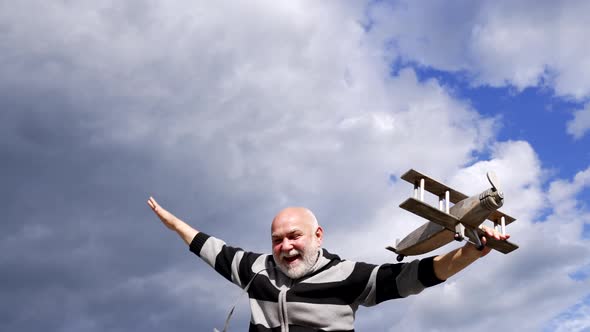 Happy Old Man Use Imagination to Pretend Flying on Wooden Plane in Sky Imagine