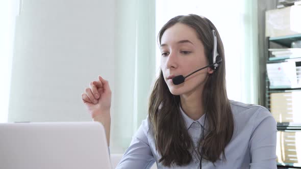 Young Woman Wearing Headphones Communicating Online Via Laptop Explaining Teaching