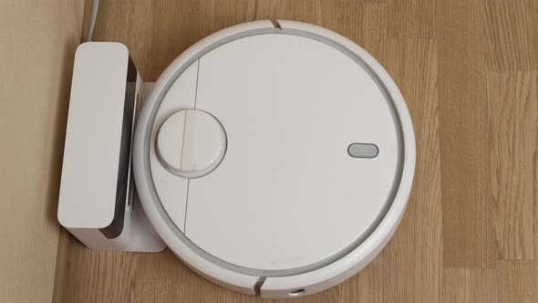 White Robotic Vacuum Cleaner Starts Cleaning From Its Charging Station