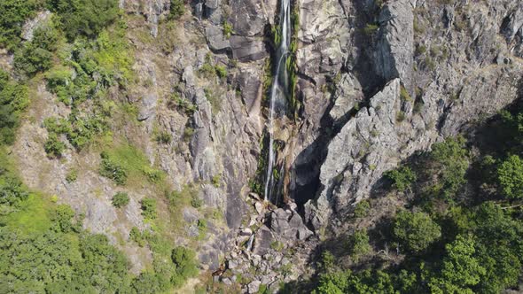 Aerial tilt up Majestic Waterfall on stone cliff, Frecha da Mizarela - Portugal