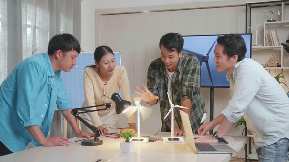 Asian Engineers Group Testing The Wind Turbine While Having A Meeting At The Office