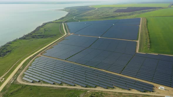 Aerial View of a Solar Panel Farm with Rows of Panels Drawing Energy From the Sun By the Lake