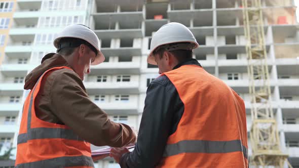 Two construction professionals discussing a construction work plan at a construction site.