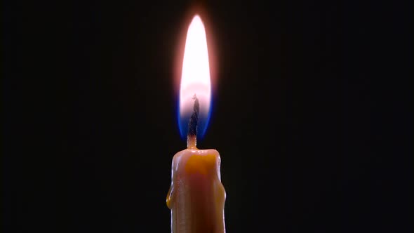 Hand with a Cigarette Lighter Ignites One Candle. Black Background. Close Up