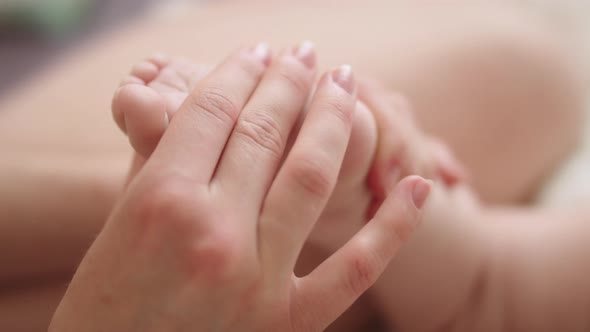 Mother Massaging and Tickling Small Baby Feet. Close Up Slow Motion Shot