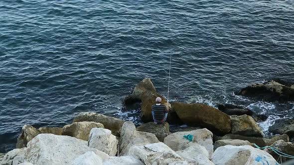 Fisherman Sitting on Huge Stones and Fishing Hobby and Relaxation Recreation