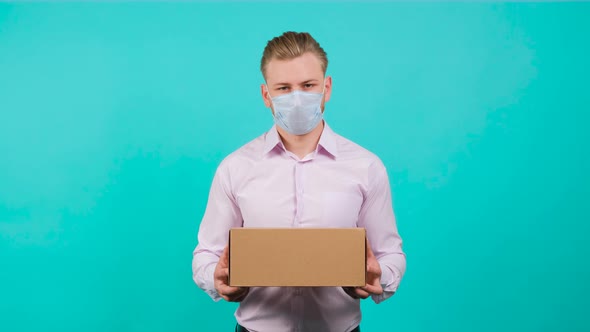 Man Wearing Face Mask While Holding a Box and Standing in the Studio.