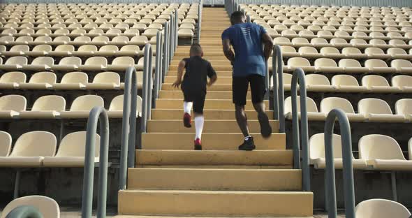 Anonymous Man and Boy Running on Steps on Stadium