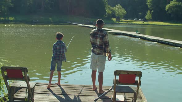 Positive Multiethnic Family with Fishing Rods Angling on Pond From Jetty