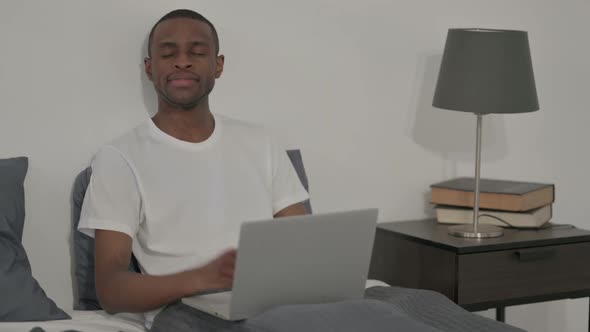 African Man Showing Thumbs Up Sign While Using Laptop in Bed