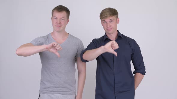 Two Stressed Young Men Giving Thumbs Down Together