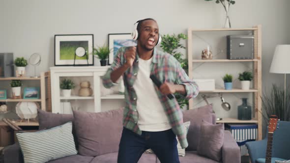 Creative African American Man Is Singing in Remote Control and Dancing Listening To Music