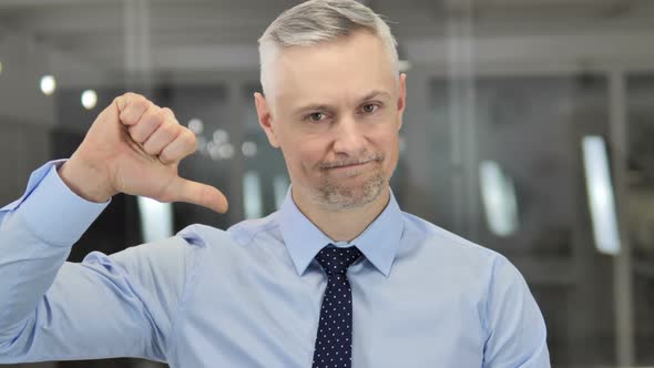 Thumbs Down By Grey Hair Businessman Looking at Camera