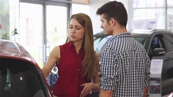 Young Beautiful Woman Talking To Her Man at the Dealership