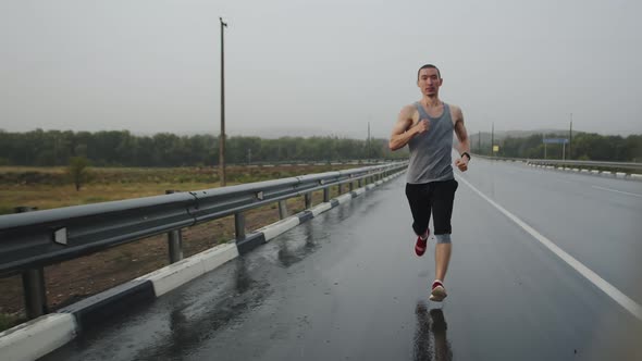 Athlete Fast Runs Along Highway During Thunderstorm Front View