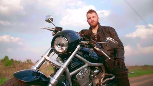 Young Man Sitting on Motorcycle on the Road at Sunset Slow Motion