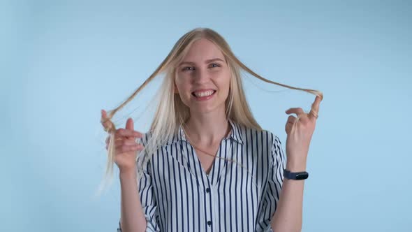 Beautiful Young Woman Playing with Her Hair on Blue Background.