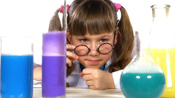 Cute Little Girl with Two Ponytails in Uniform, Correct Round Glasses Among Chemical Test Tubes, on