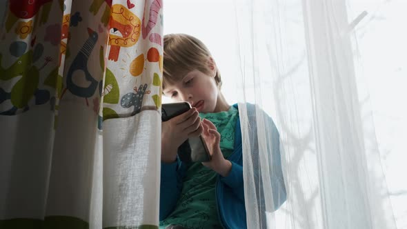 Little Boy Play Video Games By Smartphone.