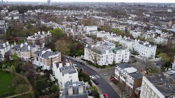 Aerial flyover beautiful district named Notting Hill in West London during cloudy day. White buildin